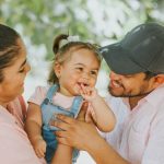 Smiling parents with baby enjoying a day outdoors in Guayaquil park.