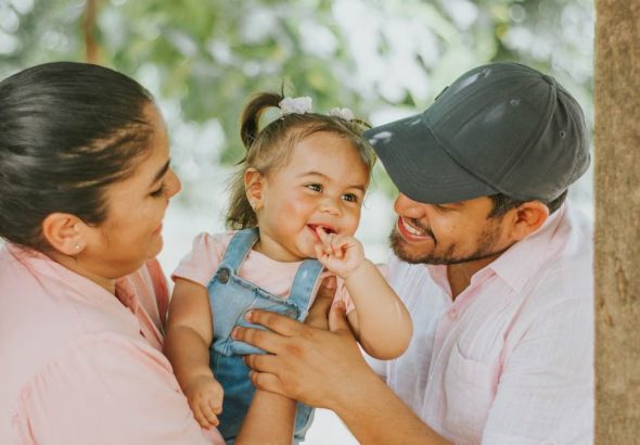 Smiling parents with baby enjoying a day outdoors in Guayaquil park.