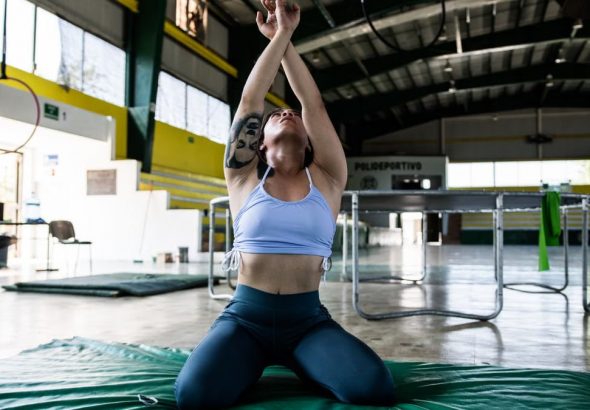 Focused gymnast in a sports hall performing exercises on a mat.