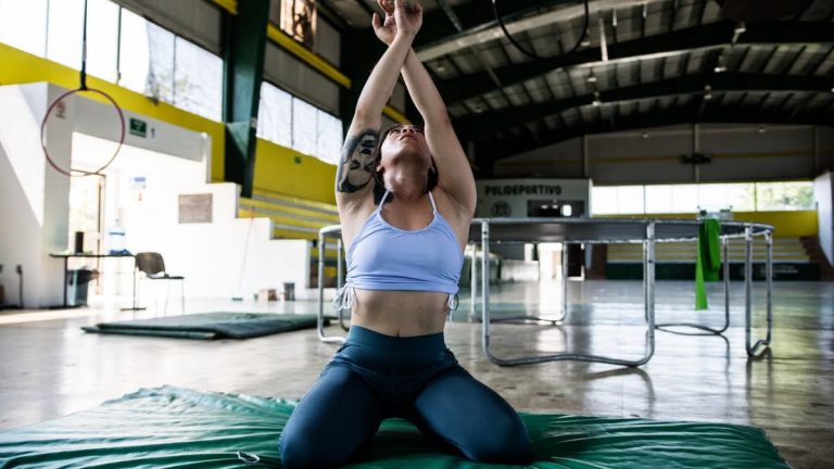 Focused gymnast in a sports hall performing exercises on a mat.